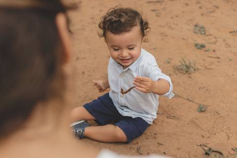 menino brincando na areia do parquinho'
