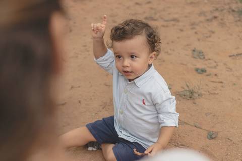 menino brincando na areia do parquinho'