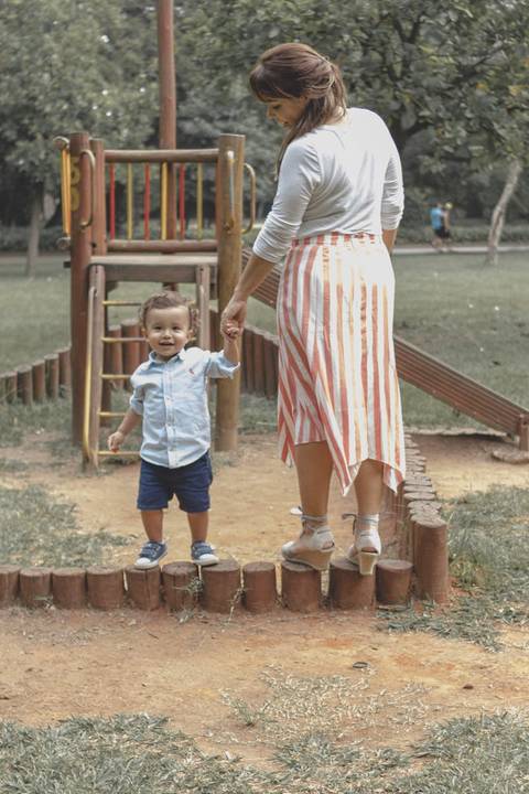 mãe brincando no  parquinho  com o filho '