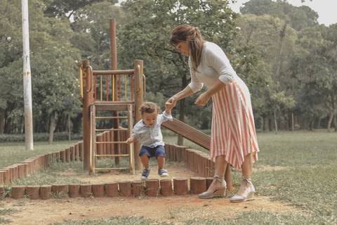 mãe brincando no  parquinho  com o filho '