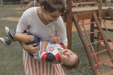 mãe brincando no  parquinho  com o filho '