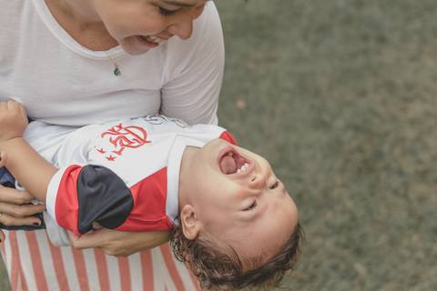 mãe brincando no  parquinho  com o filho '