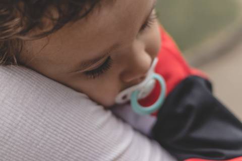 bebê dormindo no colo da mãe de chupeta'