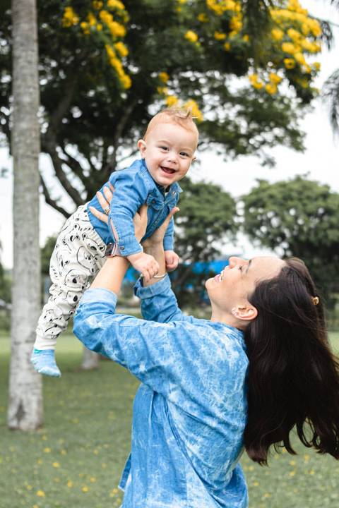 Mãe levantando filho bebê no colo no alto'