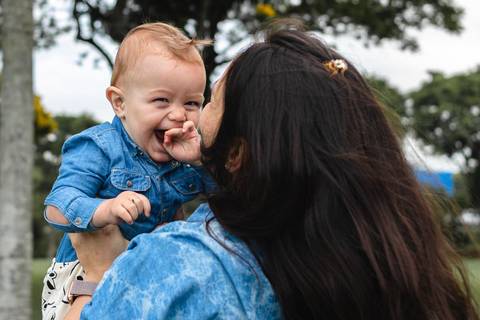 Mãe levantando filho bebê no colo no alto'