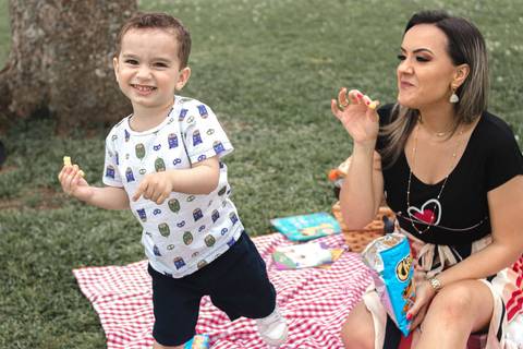 mãe e filho fazendo pique nique no parque '