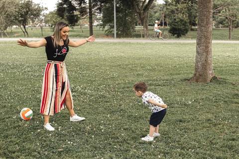 mãe e filho brincando de bola no parque '
