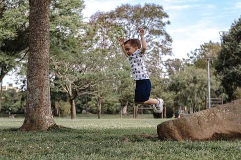 menino pulando da pedra no parque '