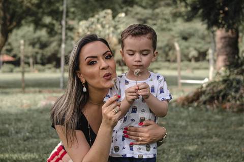 mãe e filho assoprando flor no parque '