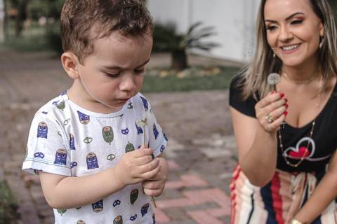mãe e filho assoprando flor no parque '