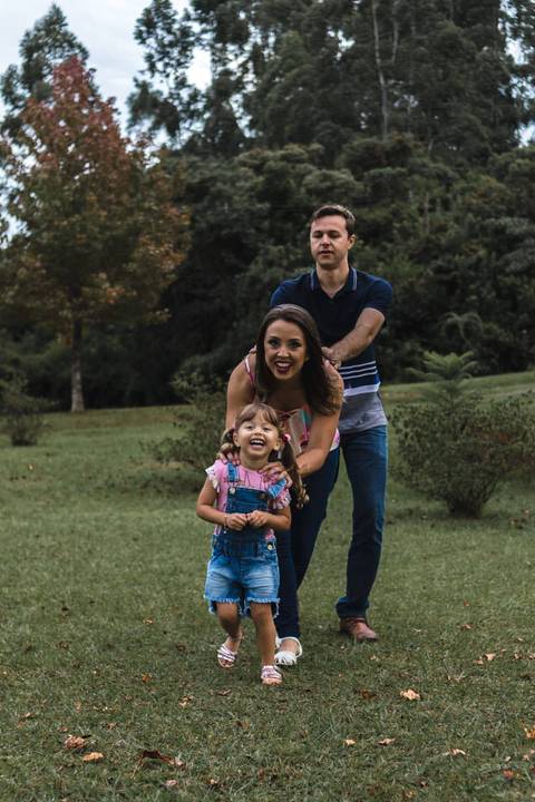 menina brincando com os pais no parque '