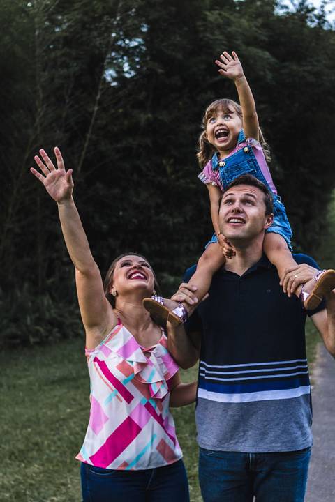 menina brincando com os pais no parque '