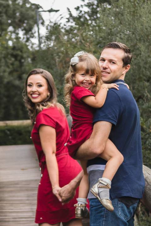 pai e mãe caminhando com a filha no colo'