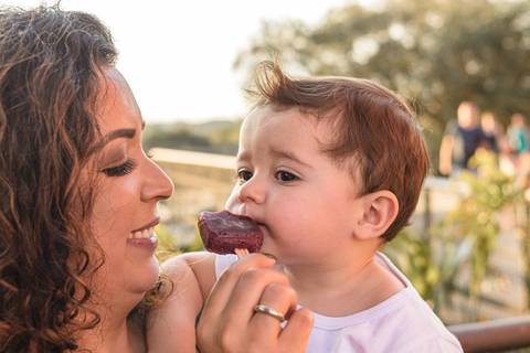 bebê chupando sorvete picolé no colo da mãe '