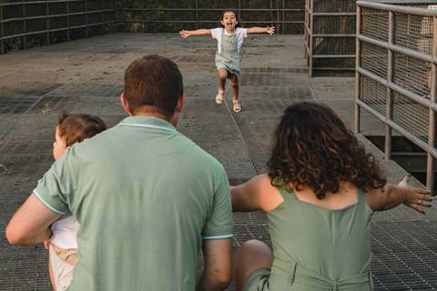 menina correndo para abraçar os pais '