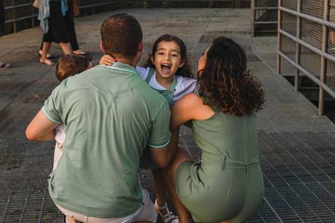 menina sorrindo e  abraçando os pais '