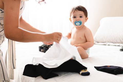mãe trocando a roupa do filho bebê '