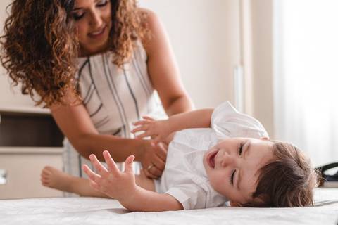 mãe trocando a roupa do filho bebê '