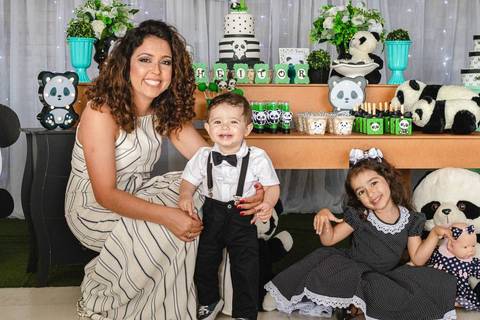 Mãe , filho e filha na frente da mesa de aniversário infantil de um ano com decoração de tema Panda'