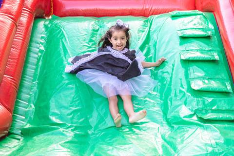 menina descendo no escorrega inflável '