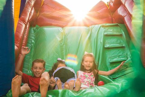 crianças descendo no escorrega inflável no pôr do sol '