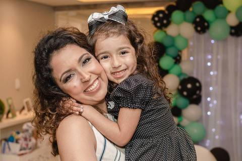 mãe com filha no colo na festa de aniversário '