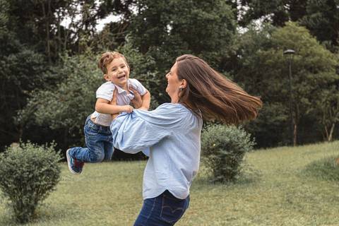 mãe brincando de rodar o filho  no gramado do  Memorial Ucraniano no Parque Tingui '