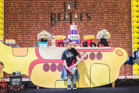 menino brincando com guitarra na decoração da festa infantil tema Beatles no Buffet Play House  Curitiba'