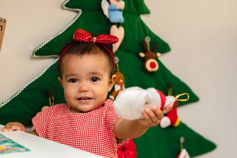 menina bebê brincando e segurando enfeite de Natal '