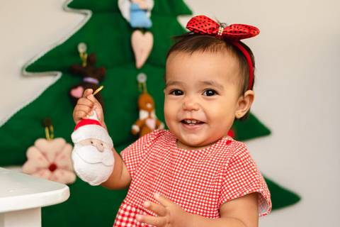 menina bebê brincando e segurando enfeite de Natal '