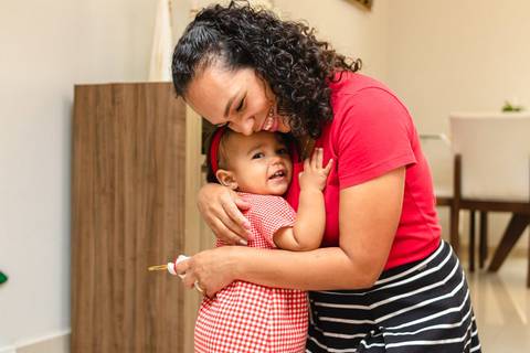 mãe e filha abraçadas em casa'