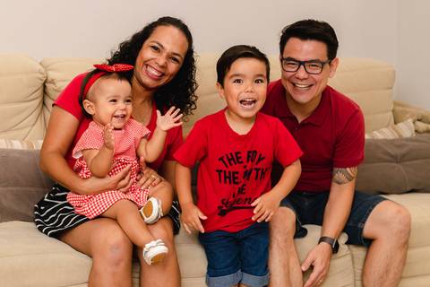 família brincando sentados no sofá de casa '