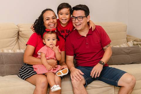 família brincando sentados no sofá de casa '