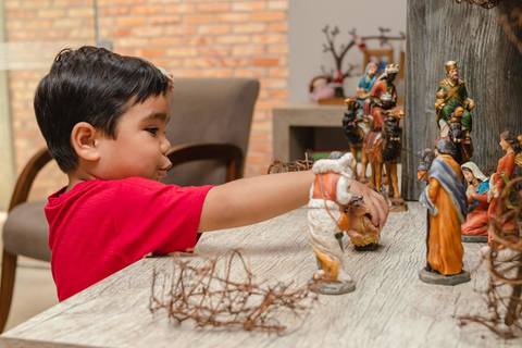 Menino brincando com presépio de Natal em casa '