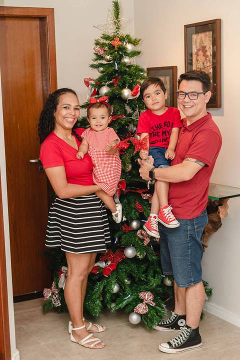 família abraçada e sorrindo na  decoração da  árvore de Natal de casa  '