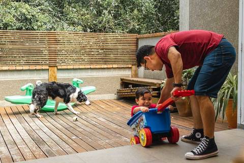 pai brincando com o filho no carrinho no quintal de casa '
