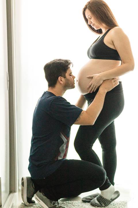marido abaixado beijando barriga da mulher grávida '