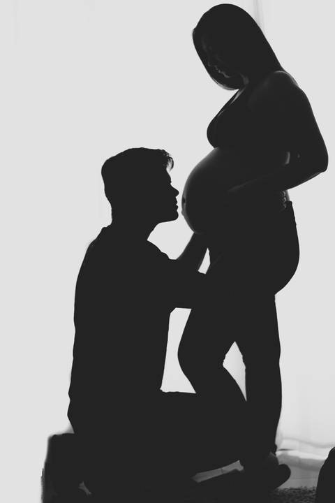 marido abaixado beijando barriga da mulher grávida '