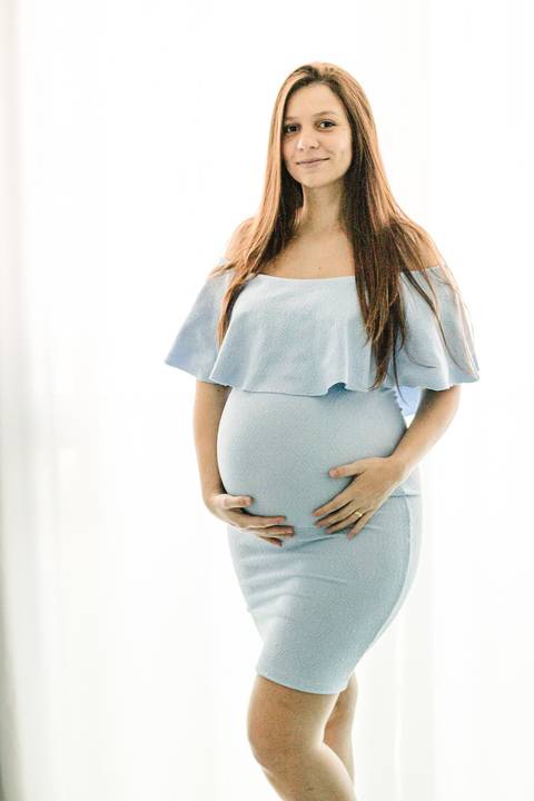 grávida sorrindo abraçando a barriga quarto do bebê'