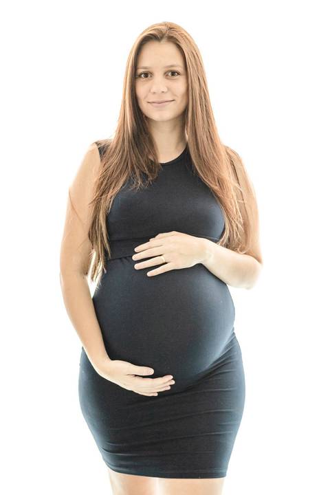 grávida sorrindo abraçando a barriga quarto do bebê'