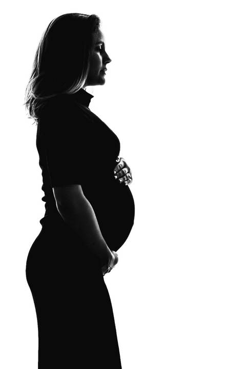 Grávida abraçando a barriga na sala de casa'