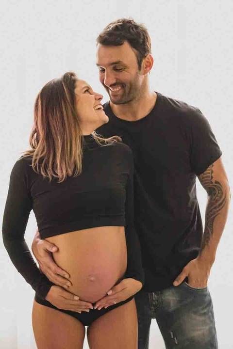 casal com mulher grávida abraçados e sorrindo  '
