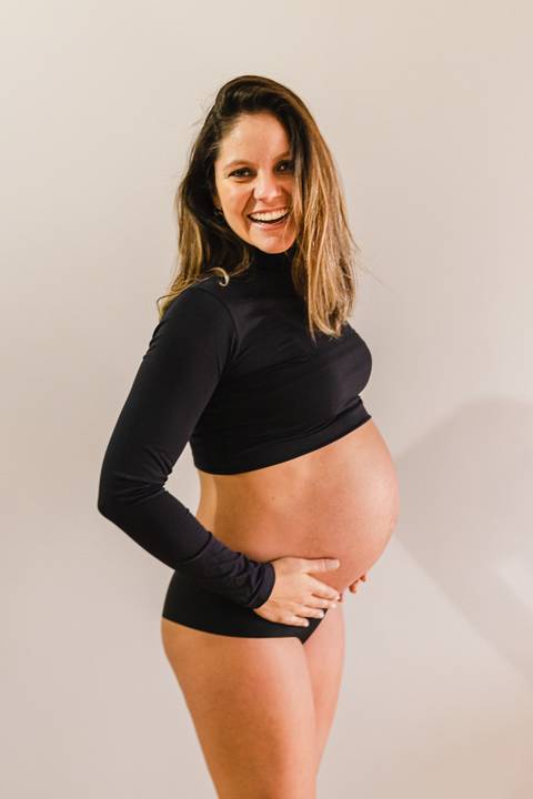 grávida olhando e sorrindo para a barriga'