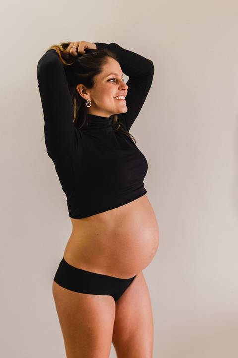 grávida olhando e sorrindo para a barriga'