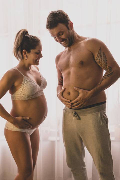 marido e  mulher grávida com a barriga na cama '