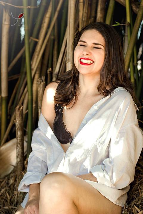 Modelo de lingerie num ensaio sensual, em meio à natureza. Rindo durante a sessão.'