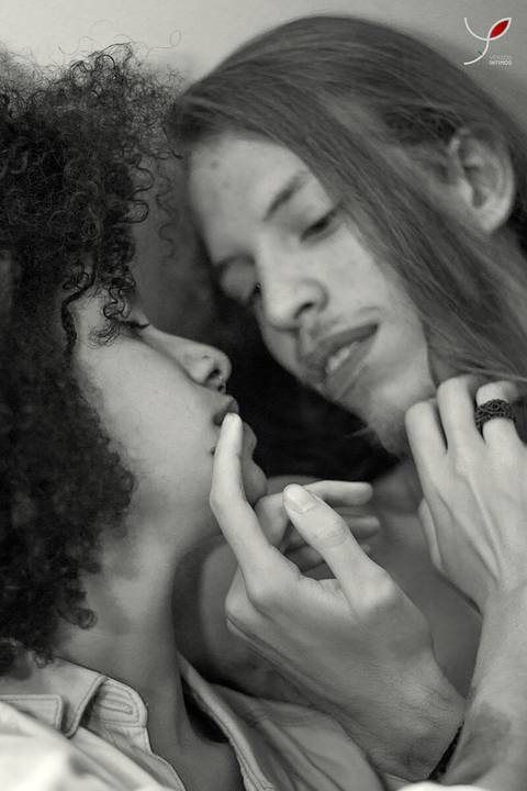 Casal olhando um para o outro. Ele sem camiseta e ela num estilo sensual. Ambos estão fazendo carinho um no outro.'