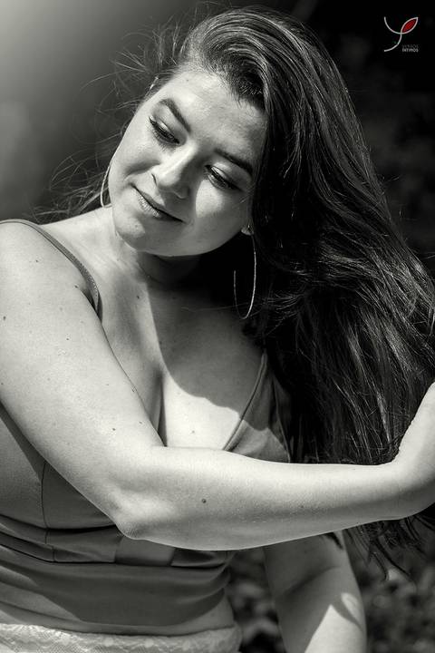 Foto em preto e branco com a modelo balançando os cabelos. Focado apenas no rosto dela e na ação.'