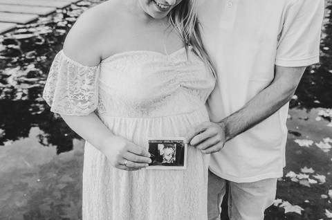 Mãos em barriga grávida com pedra em preto e branco'