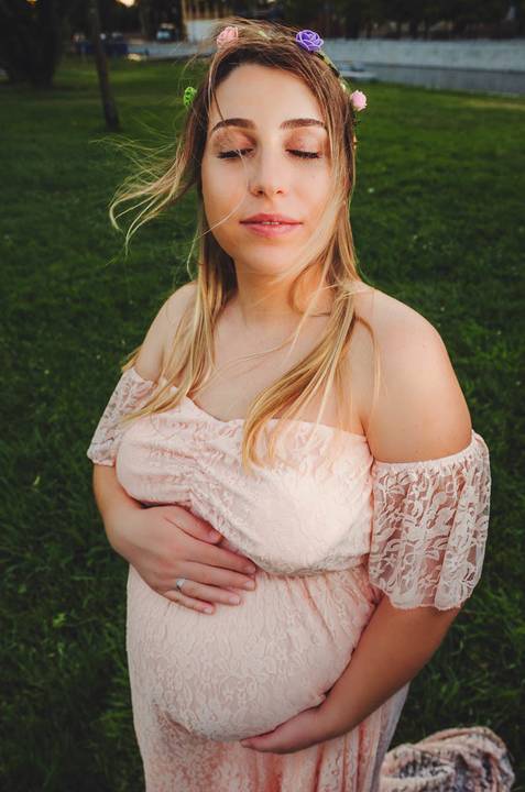 Mulher grávida em roupa clara com expressão de paz'